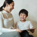 A happy mother and child enjoying quality time together with a tablet indoors.